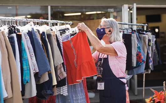 Photo of a woman hanging up clothes at the Thrift Shop by Rogue Retreat