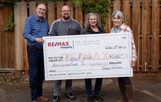 A business donating a check to Rogue Retreat